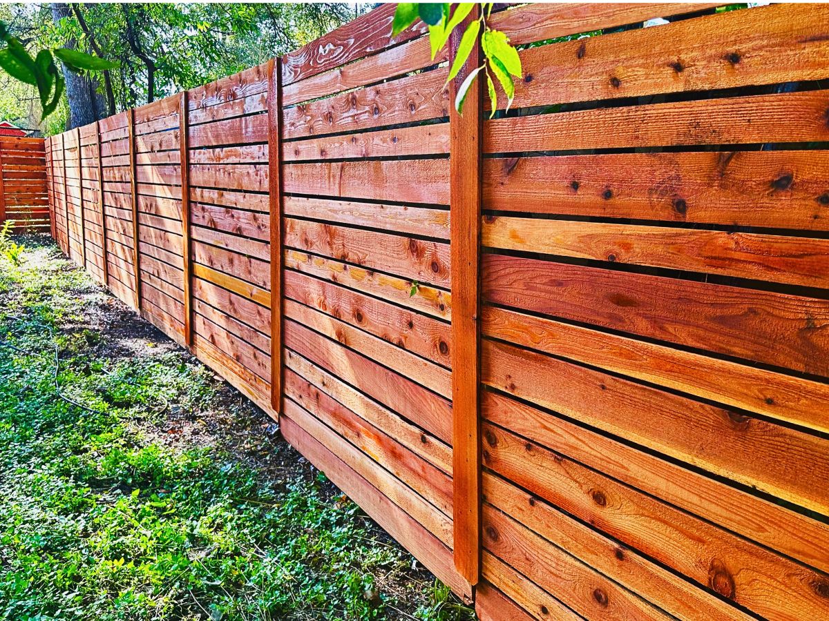Horizontal cedar wood privacy fence installed in a residential backyard with a natural wood finish.