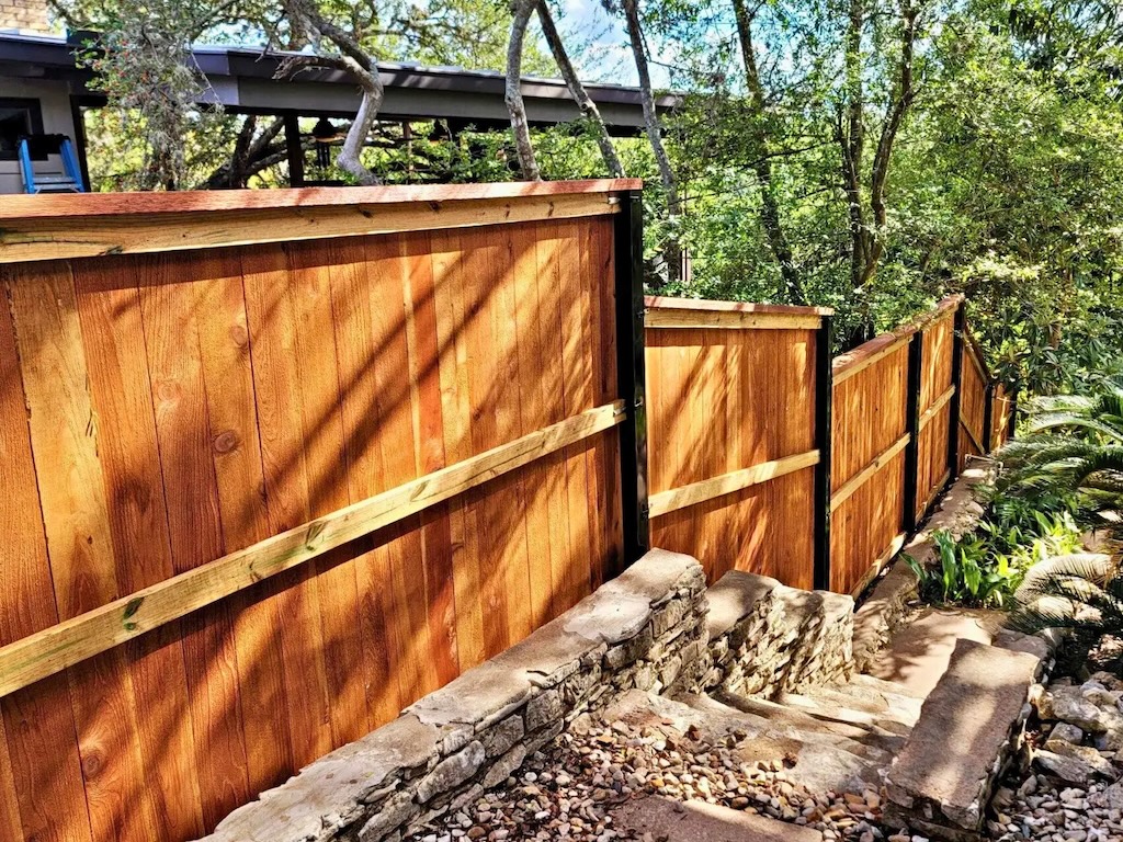 Sturdy wooden fence reinforced with exposed steel support posts