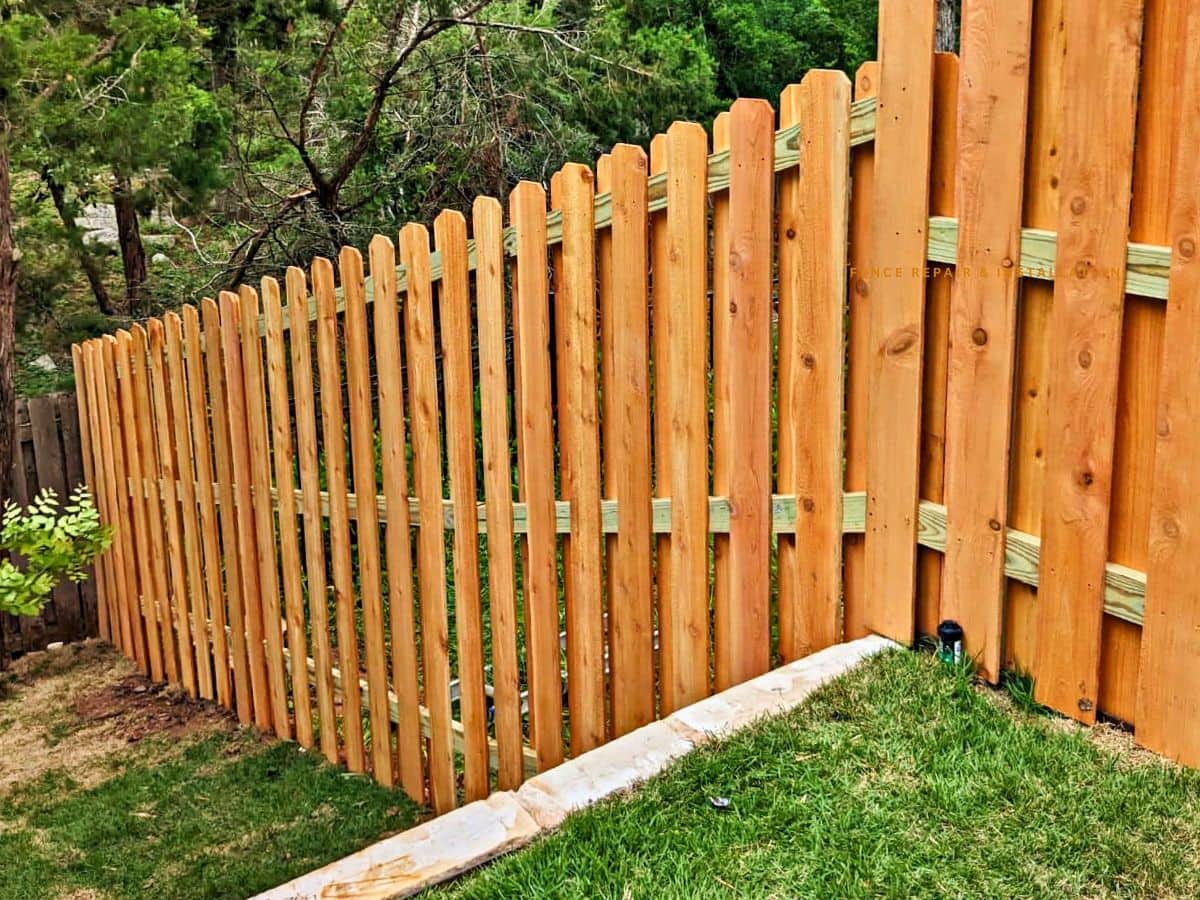 Decorative cedar privacy fence featuring horizontal wood panels and vertical slats
