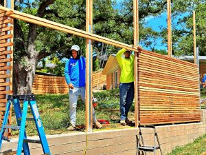 Fence builders installing a modern wood and wire mesh fence