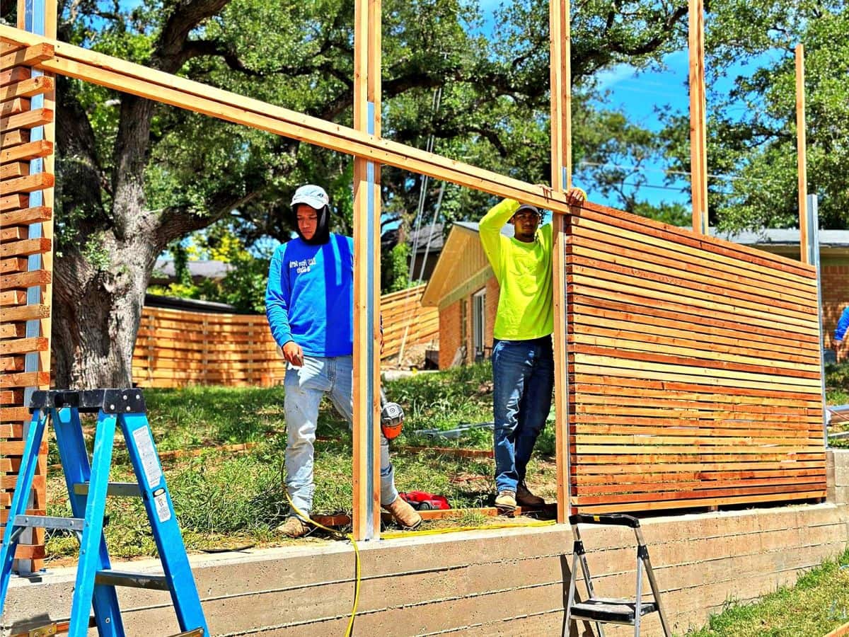 Fence builders installing a modern wood and wire mesh fence