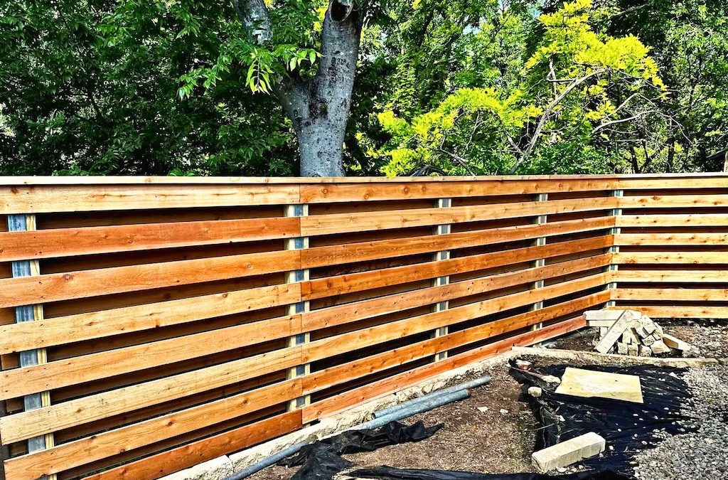 Repaired horizontal slatted wood fence with clean, even planks