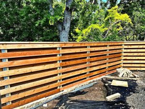 Repaired horizontal slatted wood fence with clean, even planks