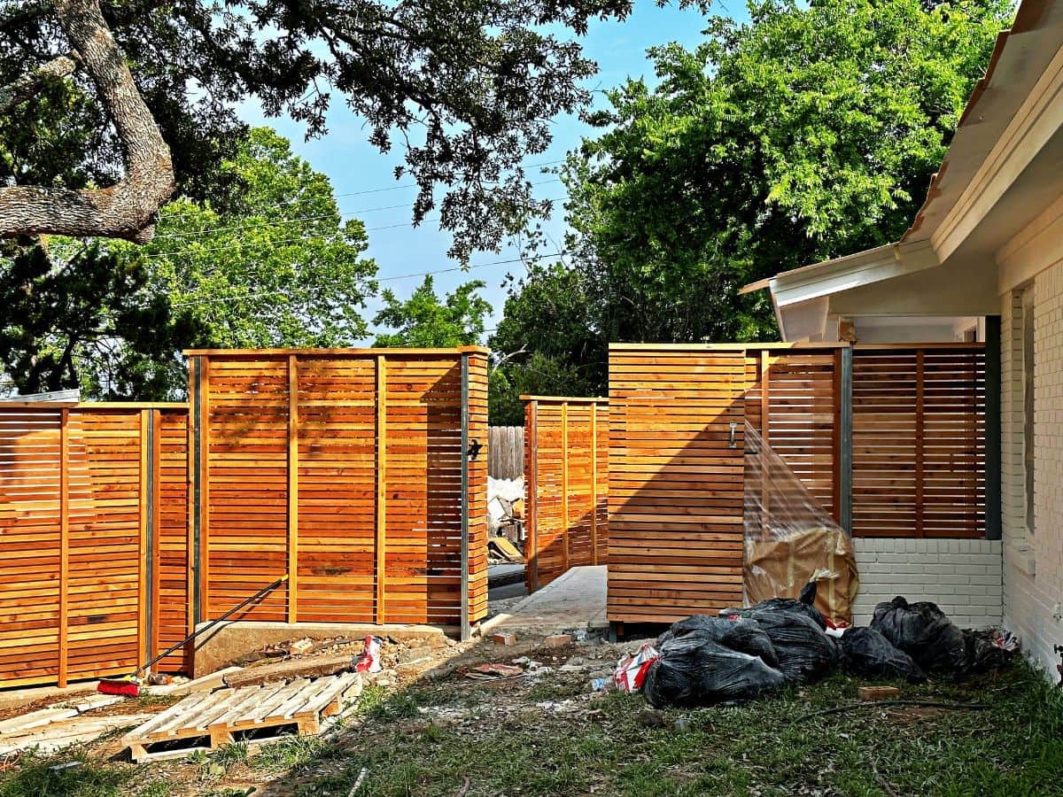Custom horizontal cedar privacy fence with black steel posts installed around a modern residential property.